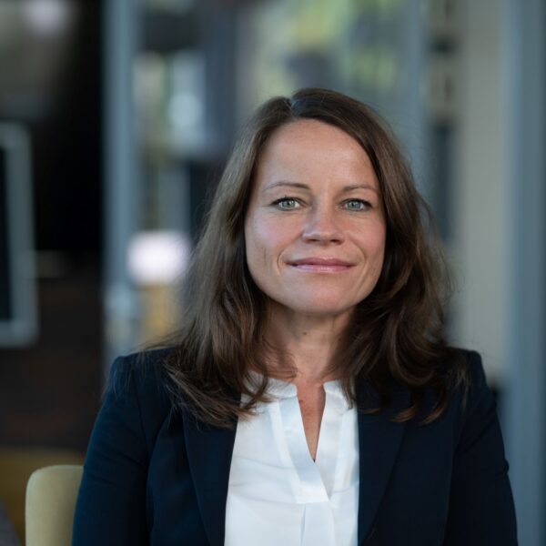 Portrait von Henrike Löser: Frau mit dunklen Haaren, Blazer und weißer Bluse blickt freundlich in die Kamera