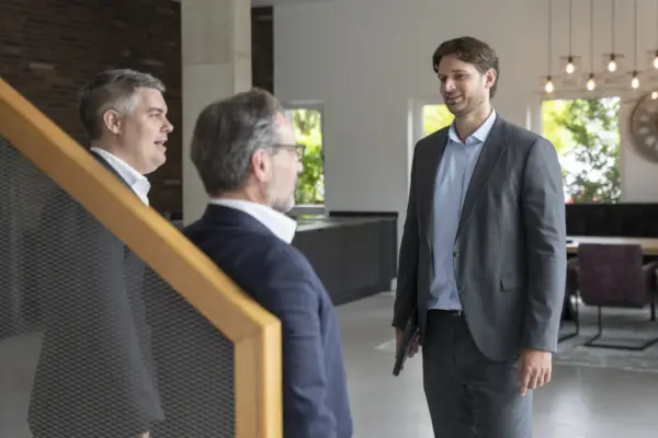 Drei Berater unterhalten sich im Foyer des aurantia-Büros neben einer Treppe